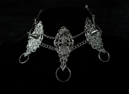 This Myril Jewels dark avant-garde metal choker, featuring punk studded details, is an exquisite piece for gothic fashion aficionados. Its intricate filigree and chain design showcase the brand's commitment to handcrafted Neo Gothic elegance. Ideal for Gothic Lolita, Gothic-chic, or whimsigoth wardrobes, it's a statement accessory for Halloween and everyday minimal goth style, exuding witchcore vibes
