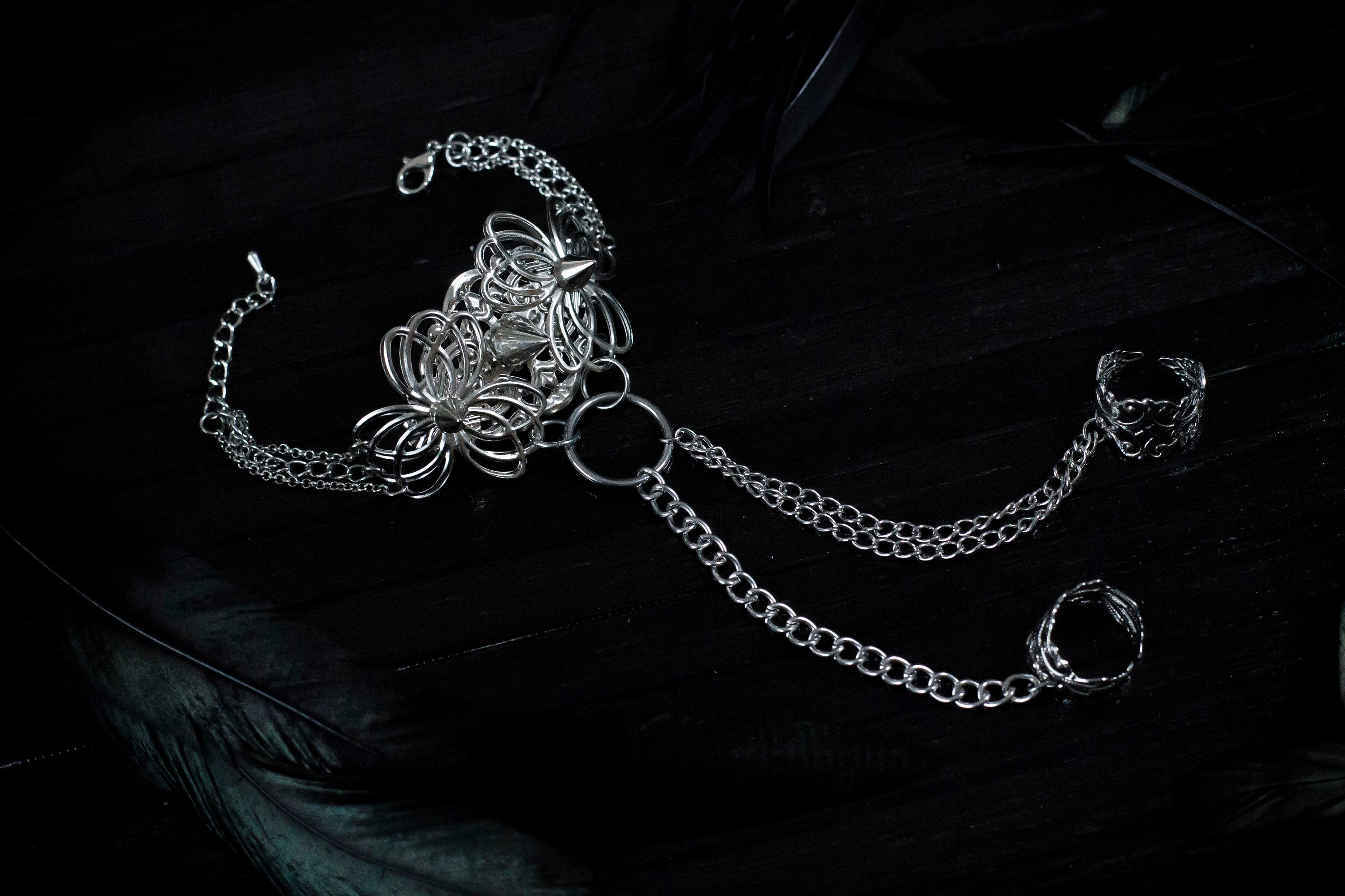 Embody the night with Myril Jewels' punk hand chain bracelet, a fusion of gothic-chic and avant-garde design. Crafted for the dark fashion connoisseur, this piece features intricate filigree work that forms an elegant ring-to-wrist chain, perfect for enhancing a Neo Gothic, Whimsigoth, or minimal goth look. Ideal for festivals, rave parties, or as a statement piece in a Witchcore collection, it's a quintessential Myril Jewel for Halloween and beyond