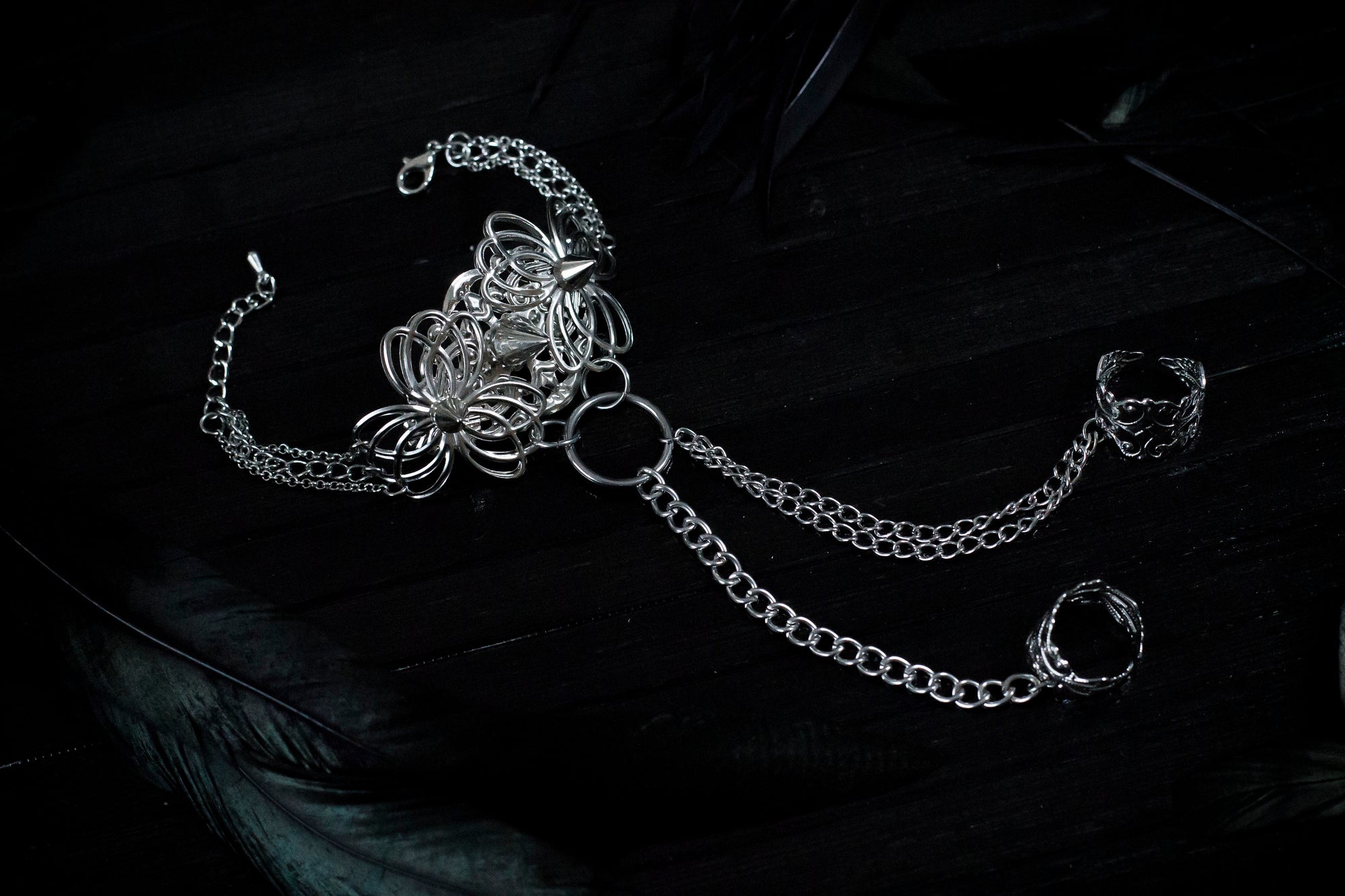 Embody the night with Myril Jewels' punk hand chain bracelet, a fusion of gothic-chic and avant-garde design. Crafted for the dark fashion connoisseur, this piece features intricate filigree work that forms an elegant ring-to-wrist chain, perfect for enhancing a Neo Gothic, Whimsigoth, or minimal goth look. Ideal for festivals, rave parties, or as a statement piece in a Witchcore collection, it's a quintessential Myril Jewel for Halloween and beyond