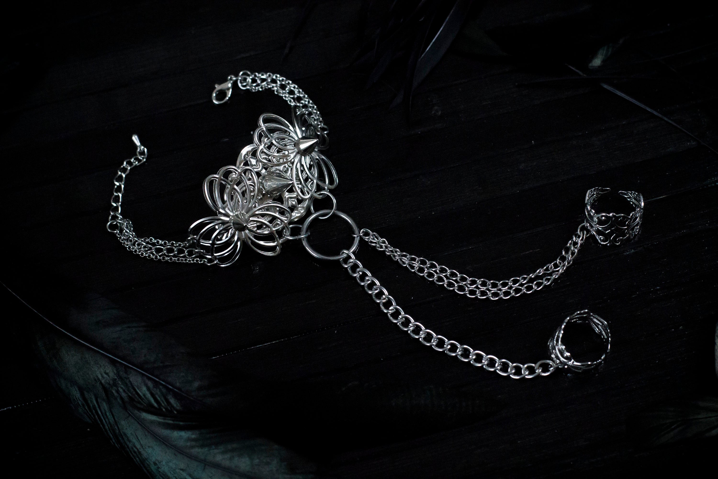 Embody the night with Myril Jewels' punk hand chain bracelet, a fusion of gothic-chic and avant-garde design. Crafted for the dark fashion connoisseur, this piece features intricate filigree work that forms an elegant ring-to-wrist chain, perfect for enhancing a Neo Gothic, Whimsigoth, or minimal goth look. Ideal for festivals, rave parties, or as a statement piece in a Witchcore collection, it's a quintessential Myril Jewel for Halloween and beyond
