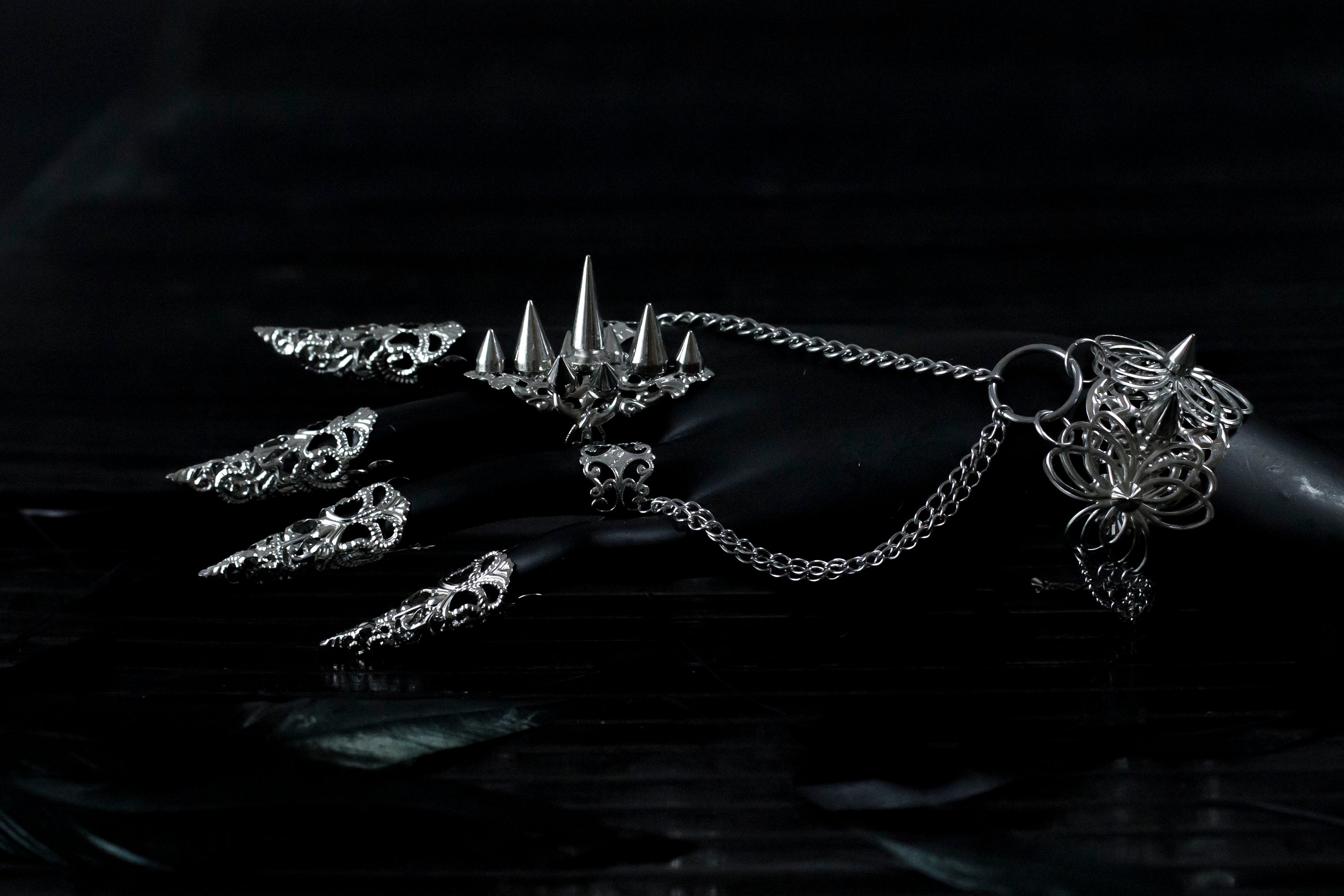 Capture the essence of punk rebellion with Myril Jewels' edgy studded ring with matching hand chain bracelet ring and nail claw rings . These bold statement pieces, with its sharp studs and metallic finish, are a must-have for lovers of dark-avantgarde and gothic accessories. Ideal for Halloween, it also complements everyday minimal goth looks, Witchcore styles, and Gothic-chic ensembles, offering a versatile addition to any Neo Gothic jewel collection