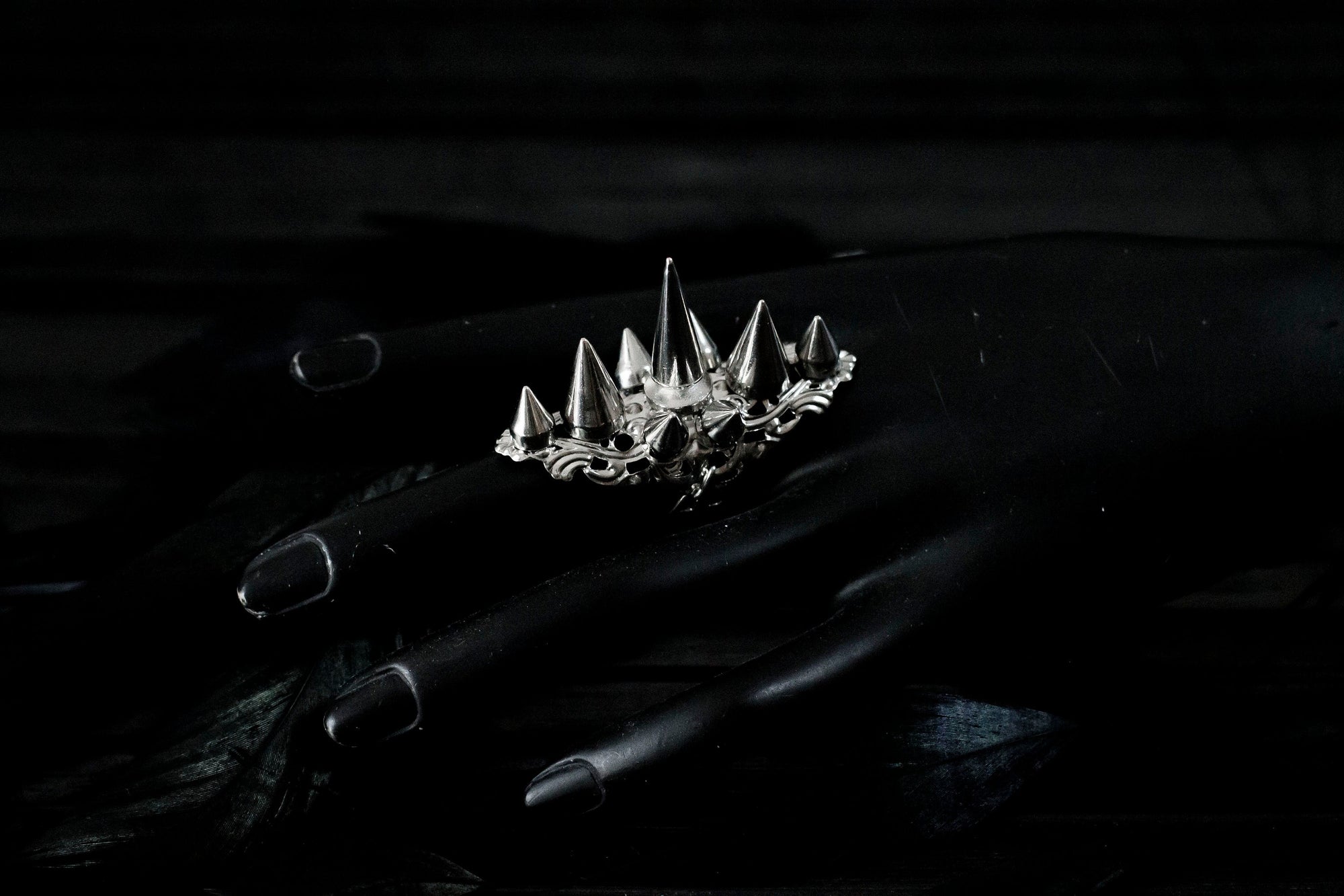 Myril Jewels' punk studded ring is a bold statement piece, meticulously crafted with a fierce array of silver spikes rising in a crown-like silhouette. This ring is a quintessential emblem of Neo Gothic style, designed for those who embody the gothic-chic lifestyle. Ideal for Halloween, it's a standout accessory for everyday wear by those who favor the Witchcore aesthetic, and a must-have for any minimal goth or Whimsigoth-inspired collection