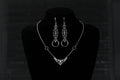 A Myril Jewels gothic necklace and matching earrings set is elegantly displayed on a black velvet mannequin. The silver necklace features a delicate filigree design, culminating in a classic gothic arch motif, paired with earrings that echo this design with an added hoop. Perfect for those who appreciate neo-goth jewelry, this set adds a touch of gothic-chic to any attire, making it ideal for Halloween, witchcore expressions, or as sophisticated everyday wear for the avant-garde individual.