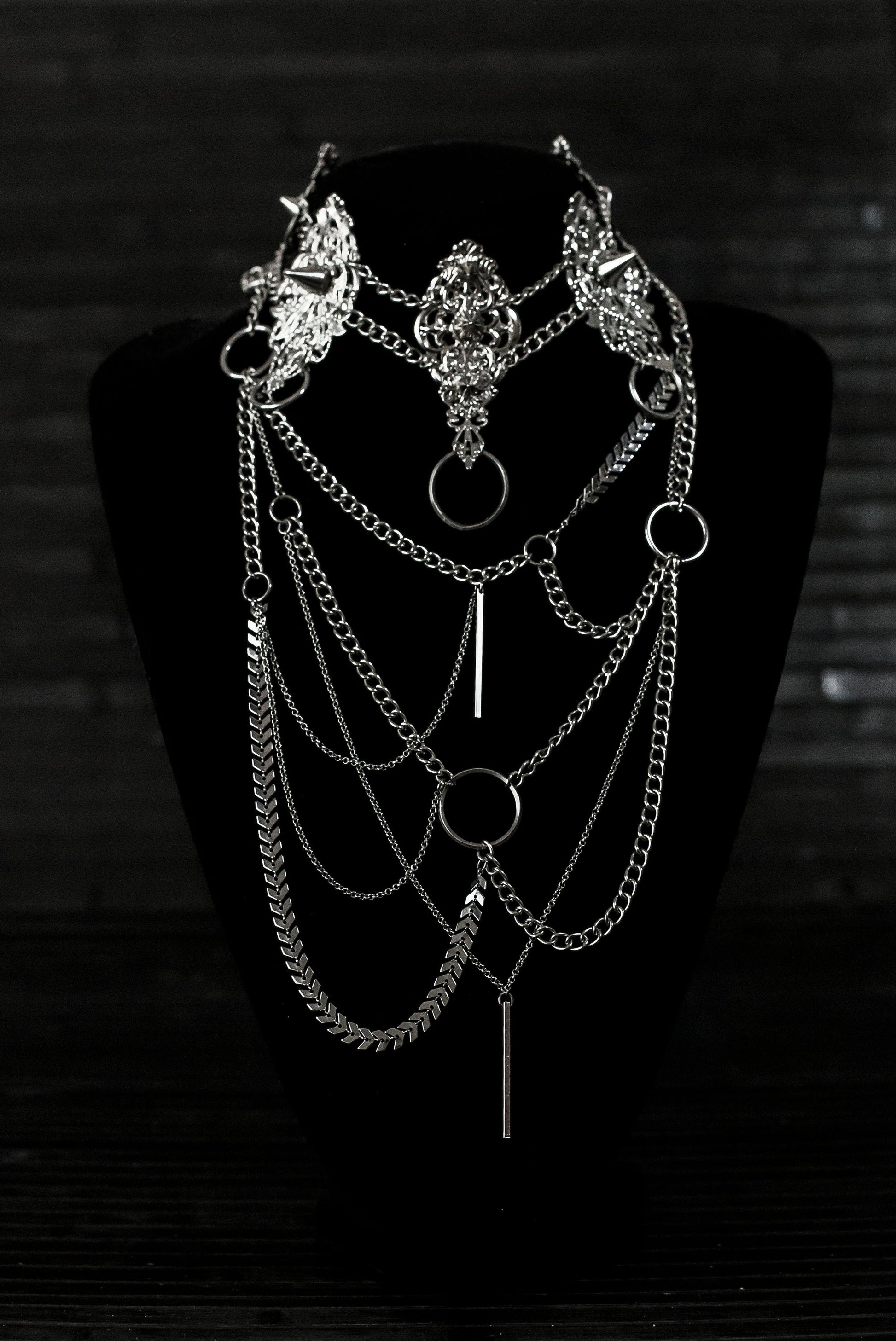 Myril Jewels presents an exquisite punk studded metal choker paired with a multi-layer long chain necklace, embodying the dark avant-garde spirit. This Italian handcrafted ensemble is a testament to the fusion of Neo Gothic flair and Gothic-chic, perfect for Halloween, everyday wear, or any whimsigoth and witchcore inspired look. The layered chains add depth to the minimal goth aesthetic, making it a versatile statement piece for alternative style connoisseurs