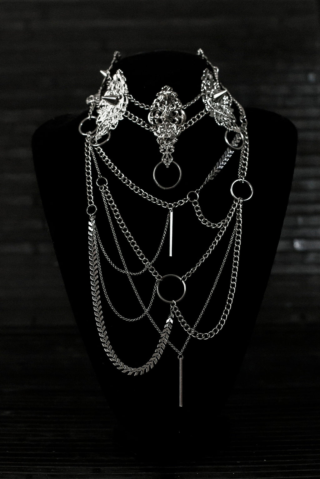 Myril Jewels presents an exquisite punk studded metal choker paired with a multi-layer long chain necklace, embodying the dark avant-garde spirit. This Italian handcrafted ensemble is a testament to the fusion of Neo Gothic flair and Gothic-chic, perfect for Halloween, everyday wear, or any whimsigoth and witchcore inspired look. The layered chains add depth to the minimal goth aesthetic, making it a versatile statement piece for alternative style connoisseurs
