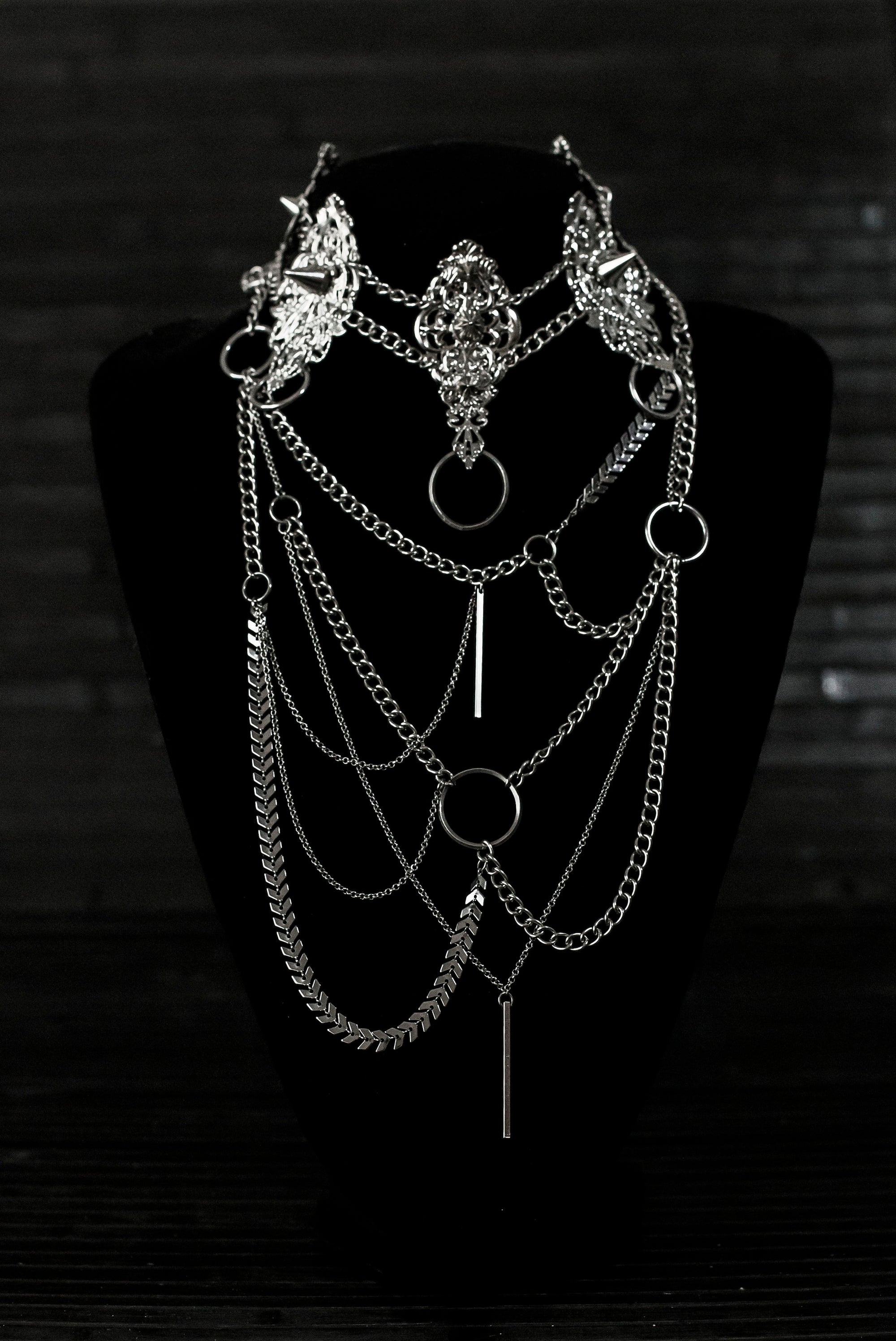 Myril Jewels presents an exquisite punk studded metal choker paired with a multi-layer long chain necklace, embodying the dark avant-garde spirit. This Italian handcrafted ensemble is a testament to the fusion of Neo Gothic flair and Gothic-chic, perfect for Halloween, everyday wear, or any whimsigoth and witchcore inspired look. The layered chains add depth to the minimal goth aesthetic, making it a versatile statement piece for alternative style connoisseurs