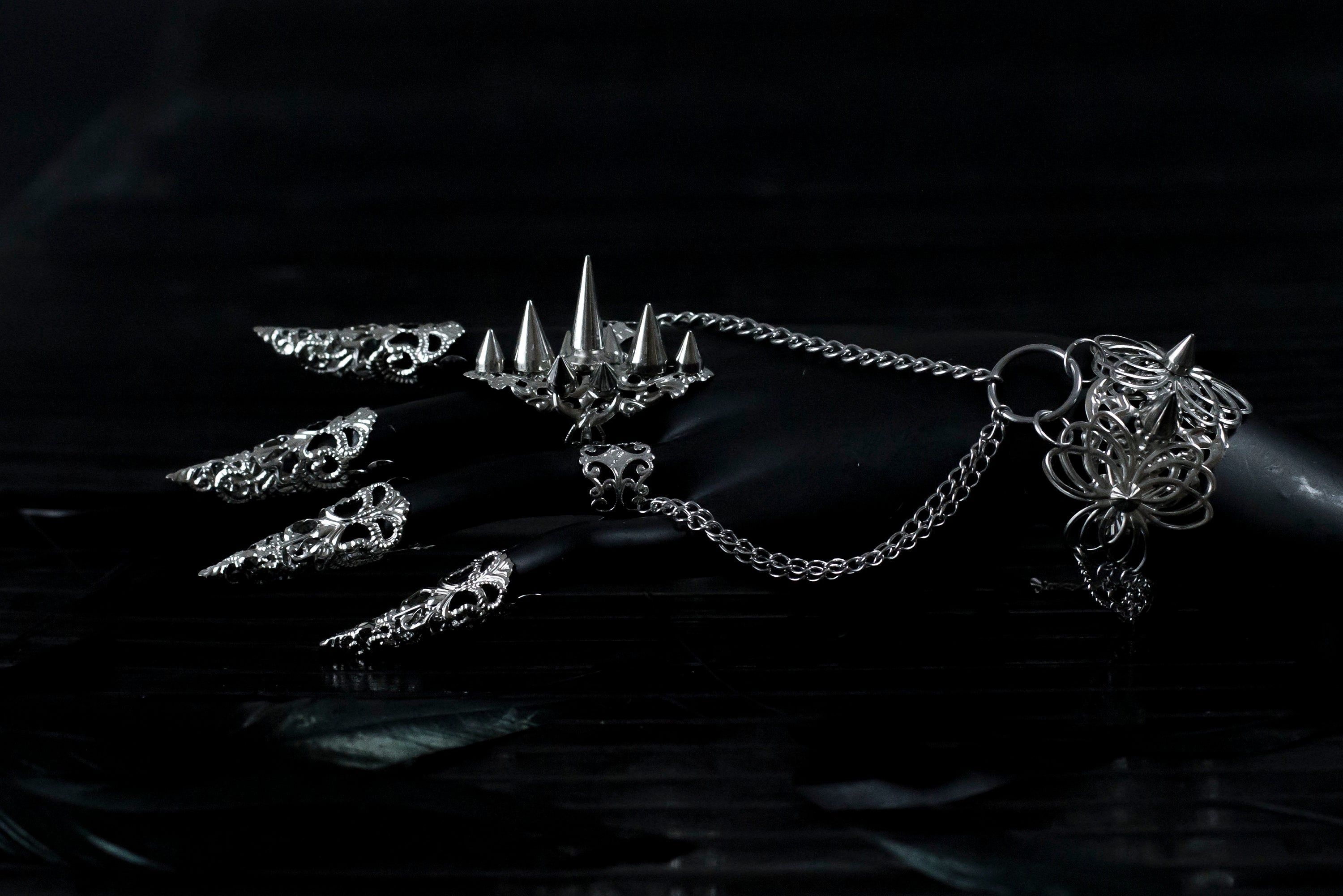 Capture the essence of punk rebellion with Myril Jewels' edgy studded ring with matching hand chain bracelet ring and nail claw rings . These bold statement pieces, with its sharp studs and metallic finish, are a must-have for lovers of dark-avantgarde and gothic accessories. Ideal for Halloween, it also complements everyday minimal goth looks, Witchcore styles, and Gothic-chic ensembles, offering a versatile addition to any Neo Gothic jewel collection
