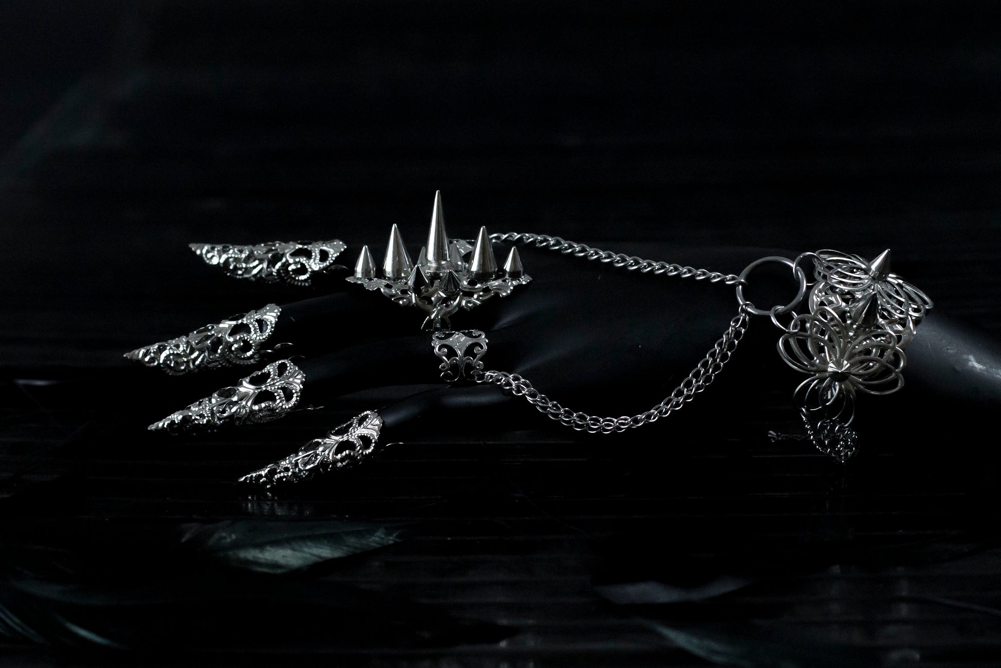 This striking Myril Jewels punk jewelry set, featuring a studded ring, a hand chain bracelet with ring, and nail claw rings, exemplifies the cutting-edge style of dark avant-garde fashion. Crafted with precision, the set's silver studs and intricate filigree cater to enthusiasts of Neo Gothic and Gothic-chic trends, making it an ideal choice for Halloween, everyday wear, and special occasions like rave parties and festivals. Each piece is designed to make a bold statement