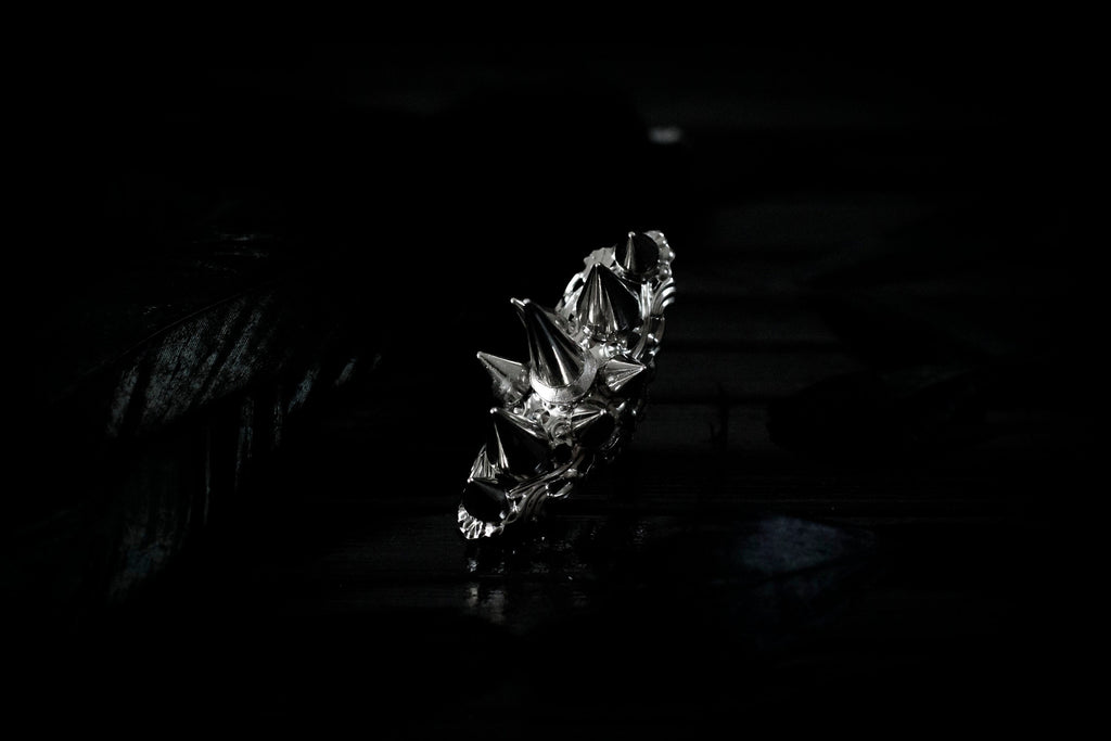 This bold Myril Jewels punk studded ring stands out with its gleaming silver spikes and intricate filigree detailing that pays homage to Neo Gothic craftsmanship. Perfect for anyone seeking a statement piece that channels Gothic-chic or Witchcore vibes, the ring is a quintessential accessory for Halloween, dramatic everyday wear, and a striking complement to any minimal goth or Whimsigoth inspired outfit.