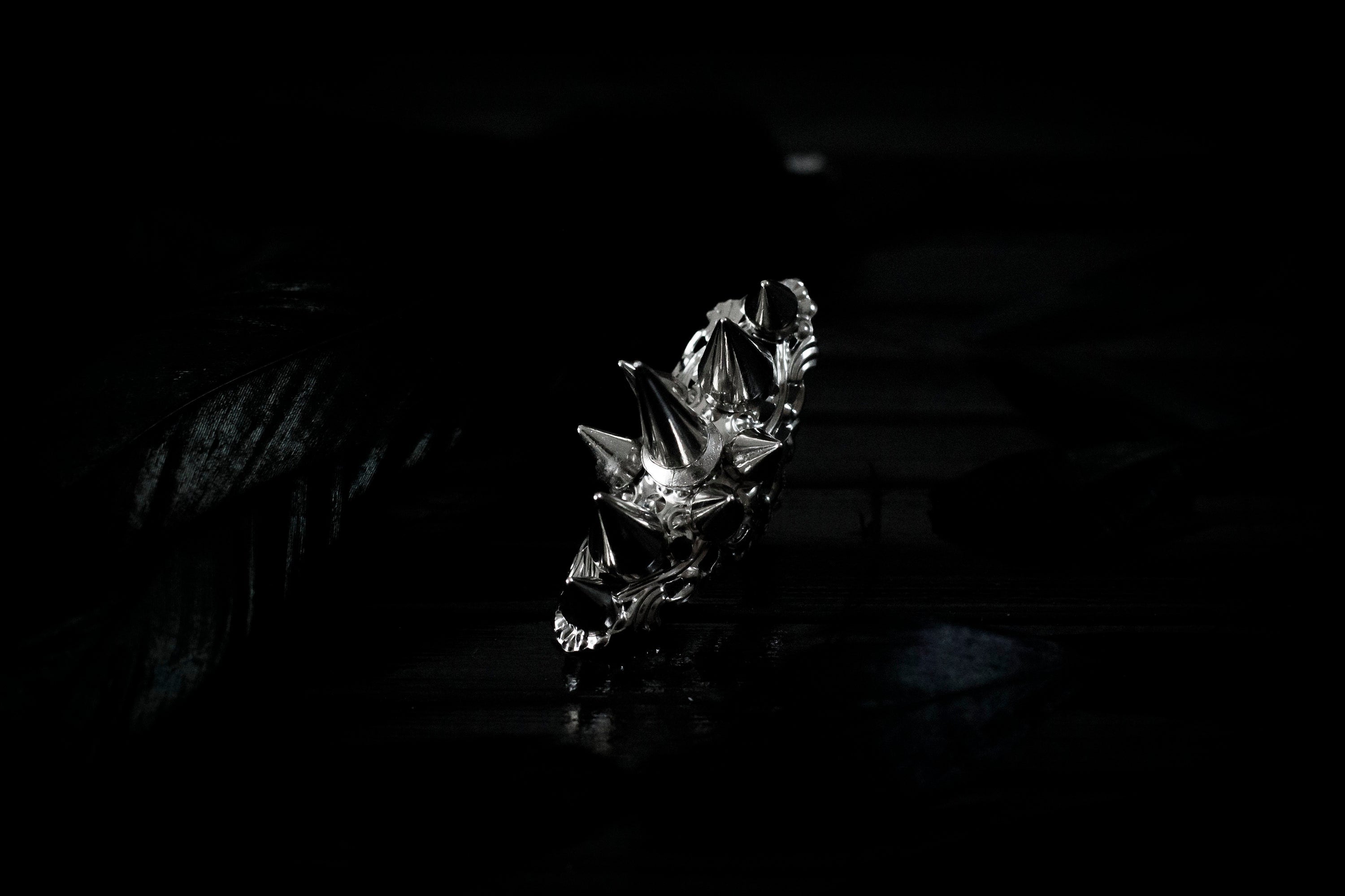 This bold Myril Jewels punk studded ring stands out with its gleaming silver spikes and intricate filigree detailing that pays homage to Neo Gothic craftsmanship. Perfect for anyone seeking a statement piece that channels Gothic-chic or Witchcore vibes, the ring is a quintessential accessory for Halloween, dramatic everyday wear, and a striking complement to any minimal goth or Whimsigoth inspired outfit.