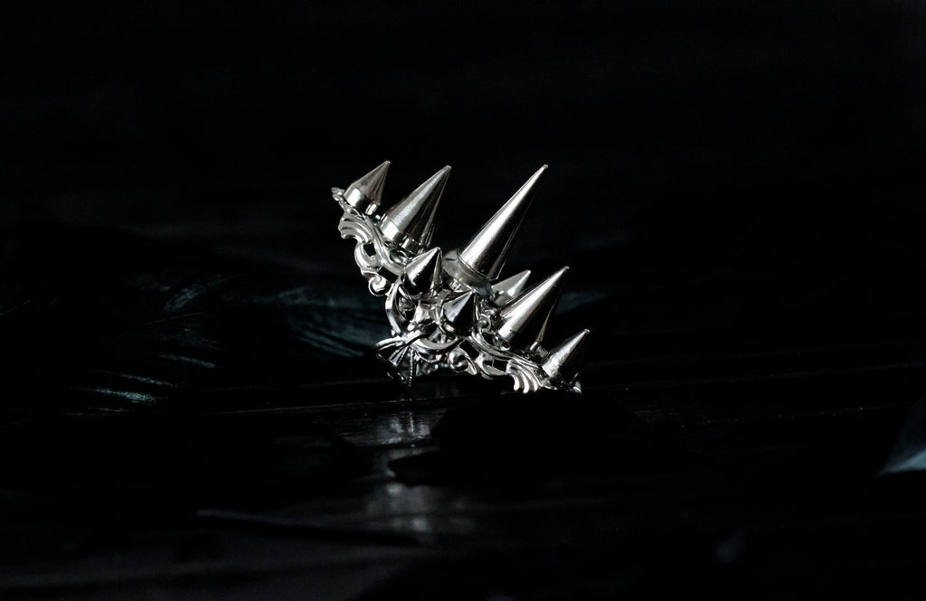 This Myril Jewels silver punk studded ring makes a bold statement with its sharp, gleaming spikes and intricate filigree detailing. Crafted for the dark avant-garde jewelry aficionado, it's a piece that commands attention, perfect for Halloween, embracing the Neo Gothic vibe, or elevating everyday wear with a touch of gothic-chic. Ideal for those who identify with the Whimsigoth or Witchcore aesthetic, or for anyone looking to add an edge to their minimal goth style.