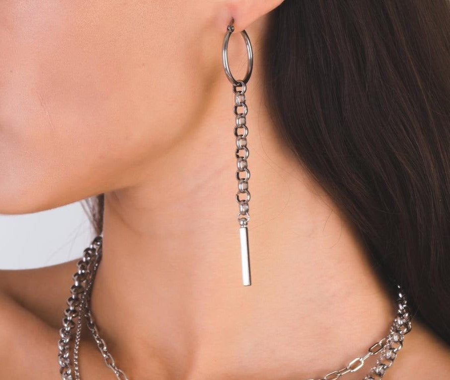 The image showcases a model wearing a pair of elegant hoop earrings with delicate long chains. These silver earrings exemplify Myril Jewels' neo-gothic aesthetic, suitable for lovers of dark avant-garde fashion. Ideal for Halloween, punk style, or everyday wear, they make a bold statement for those embracing a gothic-chic or whimsigoth lifestyle.