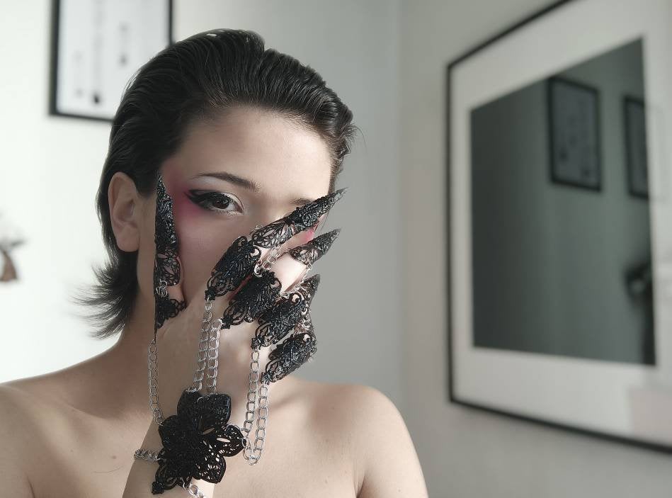 Immerse in the allure of Myril Jewels' black metal glove, a breathtaking embodiment of dark-avantgarde artistry. This hand-crafted masterpiece features elongated claw rings on each finger, creating an armor-like effect that captivates the essence of Neo Gothic style. Ideal for those drawn to the Gothic-chic and Witchcore aesthetics, this glove is a statement piece for Halloween, everyday minimal goth, and is bound to be the centerpiece in any Punk or Whimsigoth wardrobe. 
