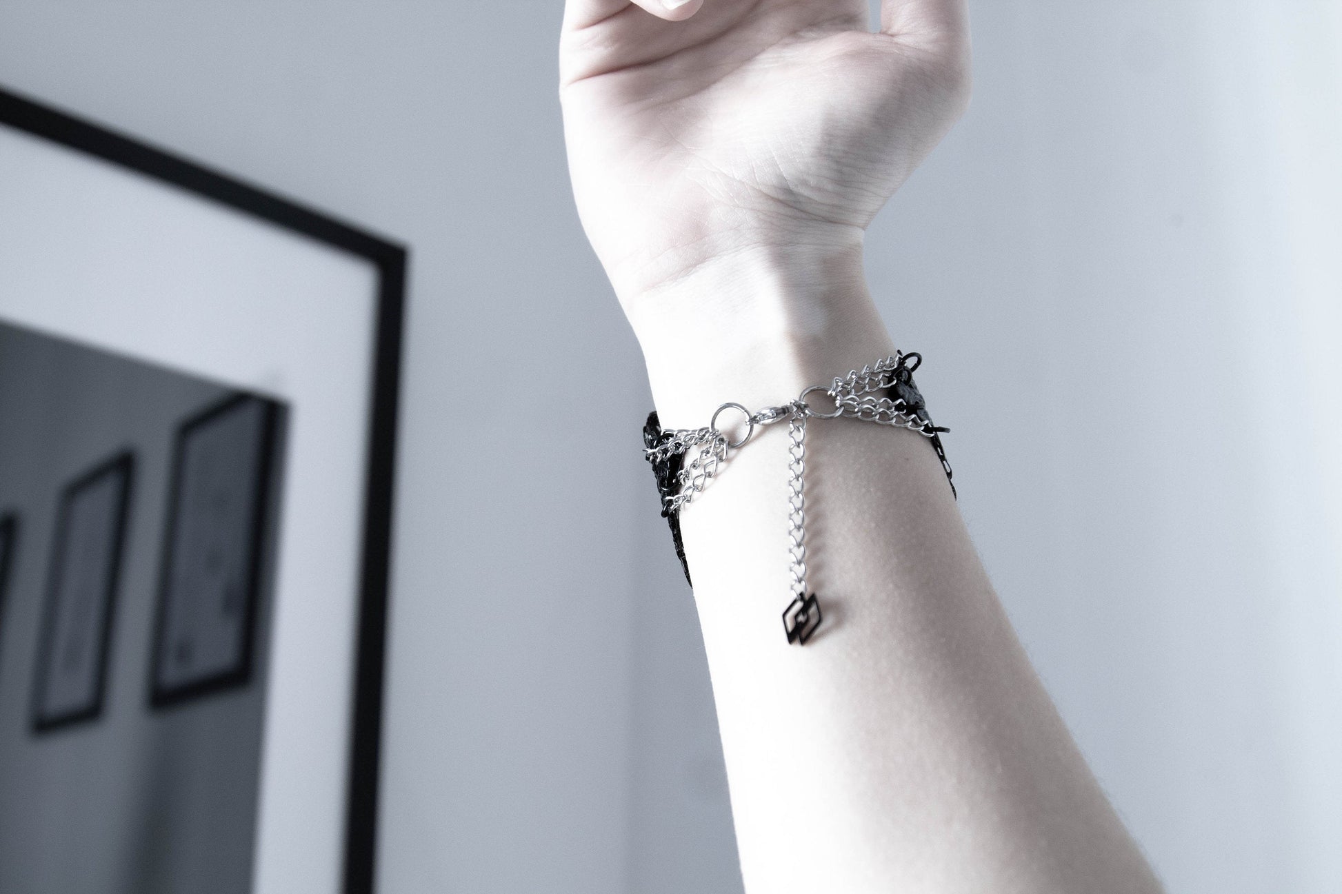 The rear of a model’s wrist is adorned with a Myril Jewels gothic bracelet featuring intricate, dark filigree that interlaces to form a lavish, ornamental design. This piece embodies the spirit of neo-gothic jewelry, a bold accessory suited for Witchcore enthusiasts, and a striking gift for those with a penchant for gothic-chic or festival fashion.