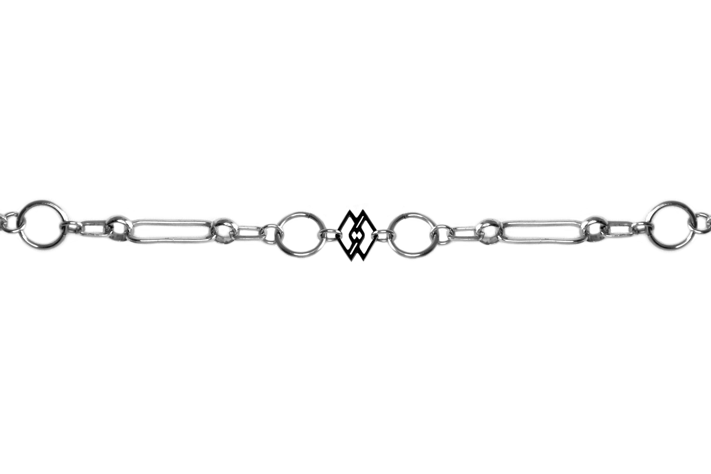 This is a sleek Myril Jewels chain-style bracelet, embodying a dark avant-garde aesthetic perfect for gothic and alternative fashion enthusiasts. The design showcases an intricate series of silver links, alternating between classic circular shapes and unique geometrical forms, culminating in a distinct rectangular charm that adds a modern twist. Ideal for everyday wear, this piece seamlessly fits into a minimal goth wardrobe while making a subtle statement. 