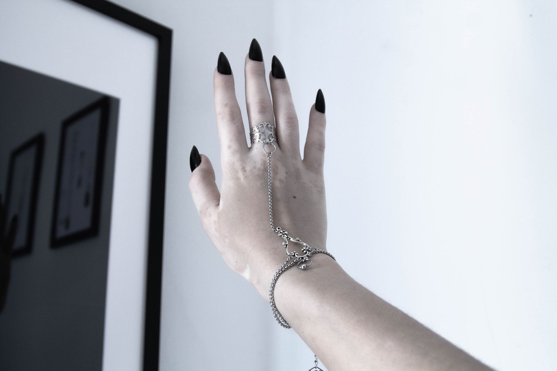 A hand adorned with a Myril Jewels slave bracelet ring, showcasing intricate craftsmanship, a perfect accessory for lovers of neo-goth jewelry seeking a dramatic addition to their everyday or festival wear